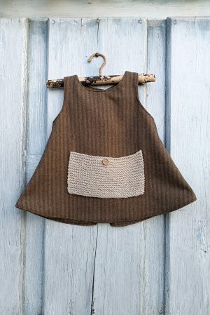 Mandil vestido corto para niña de lana y de rayas con bolso de lana pura y cierre cruzado atrás con botón de madera.
